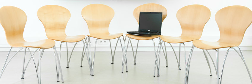 Stühle stehen im Krei, auf einem ein Laptop